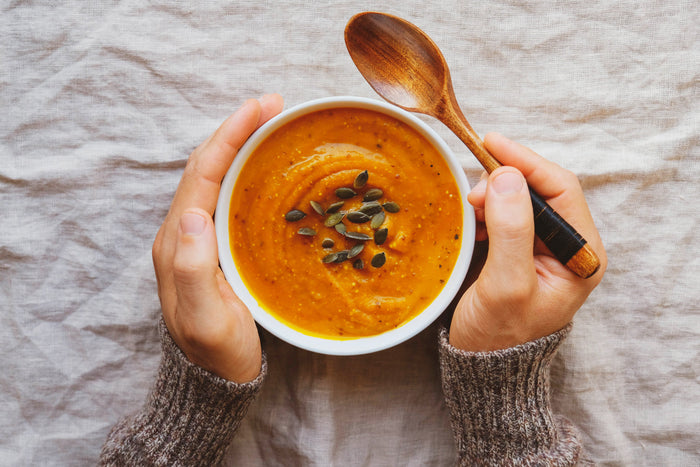 Warm autumn vegetable soup topped with seeds, symbolizing nourishing seasonal meals for balanced health during fall