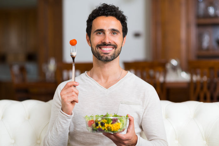 Man enjoying a colorful vegetable salad at home, practicing mindful eating to support digestion and immunity during the fall season.