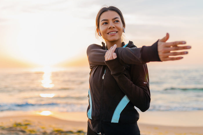 Woman stretching outdoors at sunrise, representing wellness, energy, and healthy nutrient absorption from sea moss intake.