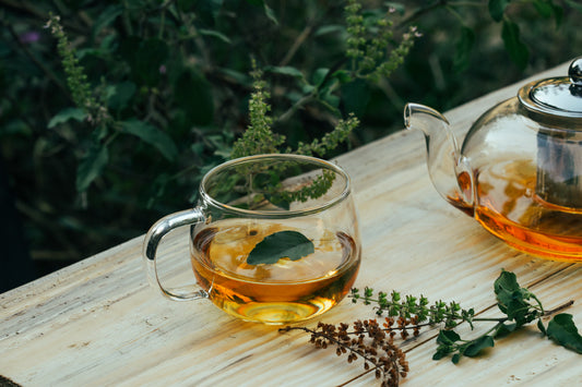 Warm herbal tea with fresh leaves on a wooden table, representing simple winter nourishment habits that support overall wellness.