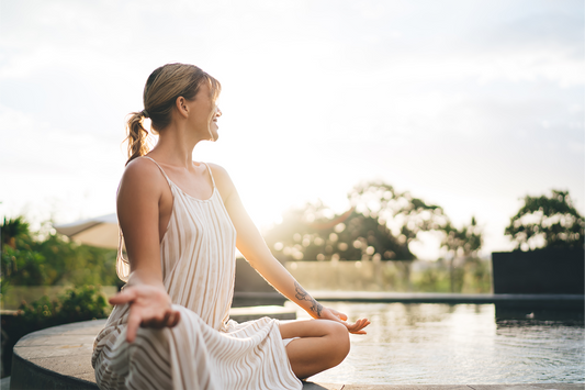 Woman meditating outdoors near water symbolizing balance, wellness, and the health benefits of liquid zinc supplements