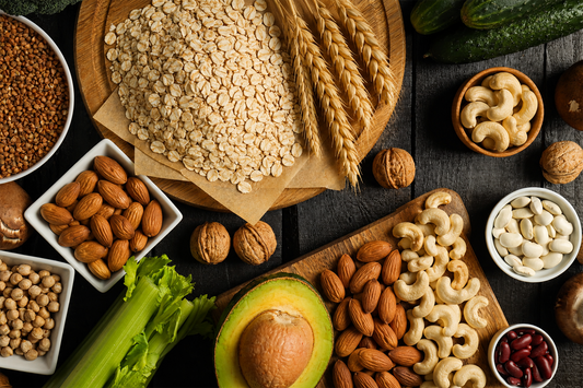 Assortment of zinc-rich foods including oats, nuts, legumes, avocado, and grains on a wooden table.
