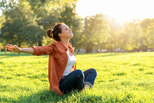 Woman enjoying sunlight in a park showing mindfulness, relaxation, and healthy lifestyle habits for overall wellness