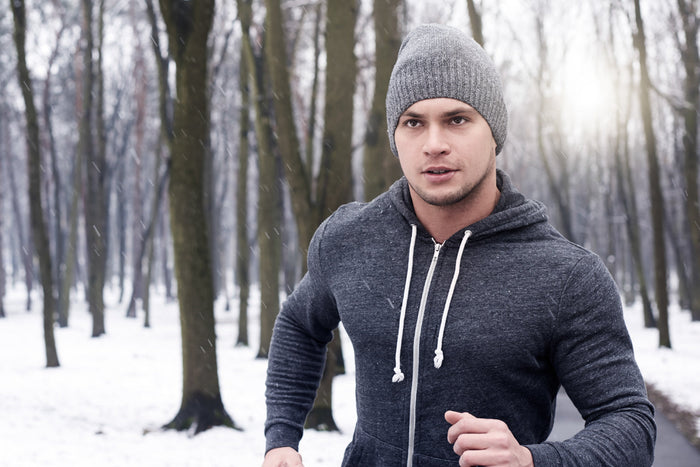 Man jogging outdoors in winter wearing warm clothing, representing seasonal fitness routines and winter wellness supported by essential nutrients like zinc