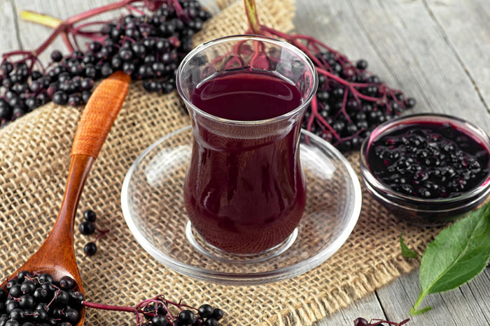 Homemade elderberry tea served in a glass cup with fresh elderberries, a soothing drink for immune support.