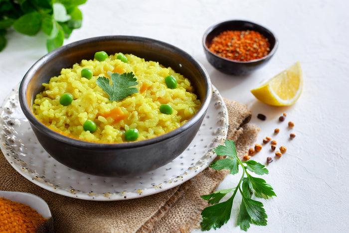 Healthy lemon-ginger khichdi served with green peas, herbs, and lemon wedge, showcasing comforting one-pot rice and lentil meal.