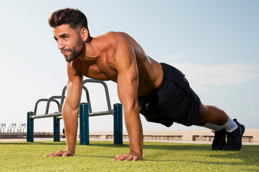 Fit man performs a plank exercise on grass outdoors, demonstrating core strength and physical fitness during an outdoor workout session.