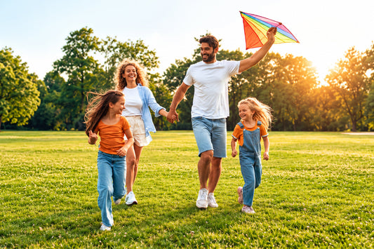 Family enjoying outdoor activities in a sunny green park, representing overall wellness, active living, and the role of essential nutrients like zinc in health.