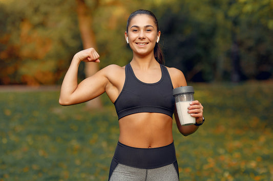 Active woman holding a protein smoothie after exercise, illustrating healthy nutrition, recovery, immune support, and the wellness benefits of colostrum supplementation.